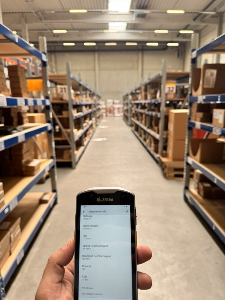 Handscanner zeigt WLAN-Werte in einer Lagerhalle